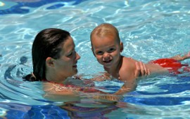 A child enjoying swimming lessons with Mom.