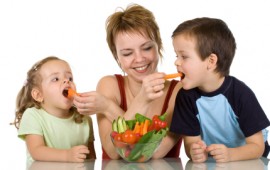 Woman feeding kids with vegetables